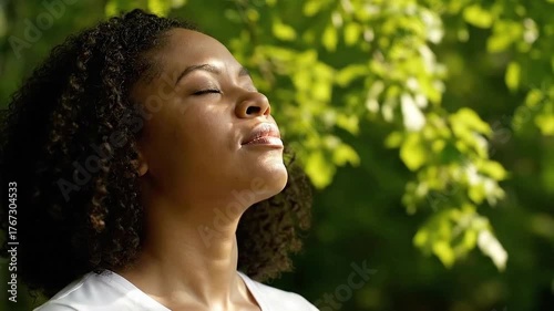 Woman Meditating with Eyes Closed in Nature Sunlight with Green Leaves Background and Soft Lighting for Relaxation and Spiritual Concept Stock Footage Video Optimized for Adobe