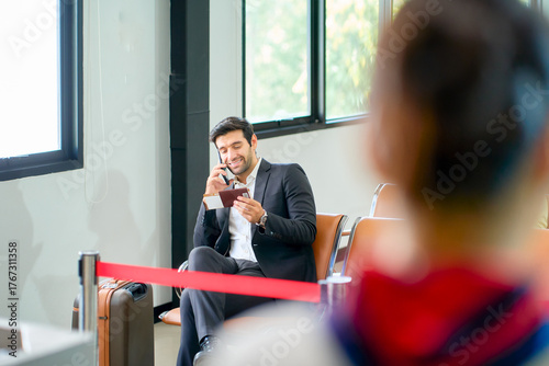 A businessman talk to mobile phone while waiting at airport seat for check in service to travel by airplane which airline business service.