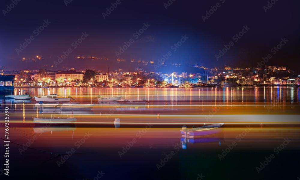Fototapeta premium Resort town of Fethiye city lights reflection on the water with boat - Fethiye, Turkey