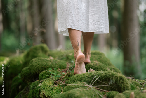 Natural close-up of female feet walking barefoot on mossy ground in a quiet forest atmosphere