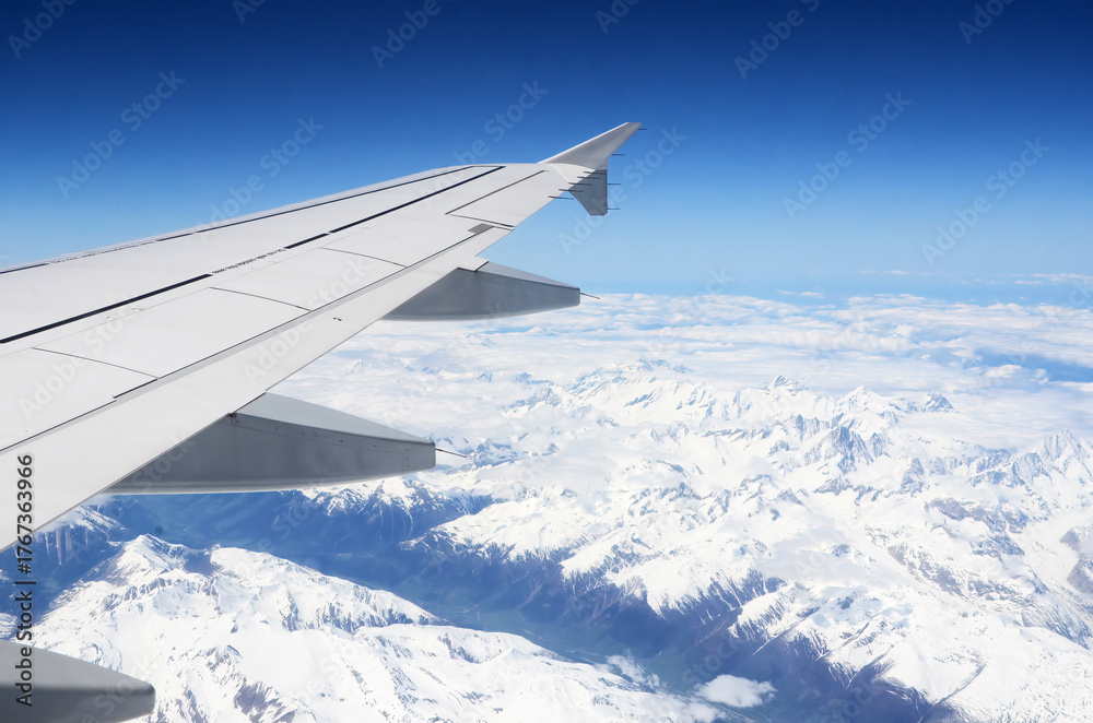 Obraz premium View from an airplane window flying over snowy alps mountains