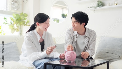 貯金箱にお金を入れるアジア人のカップル