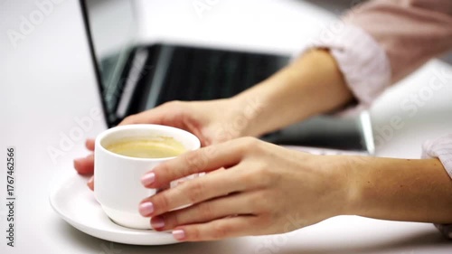 working on a laptop, drinking coffee