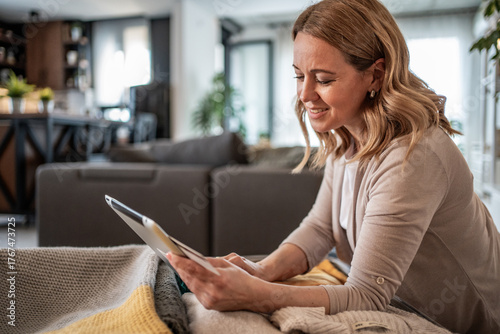 Woman using digital tablet at home surfing internet