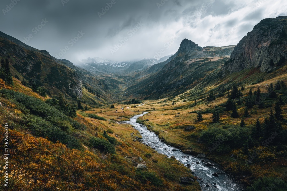 Fototapeta premium Picturesque mountain landscape with meandering river, golden-green valley, dramatic clouds, and snow-capped peaks, capturing the essence of autumn's beauty and nature's majesty