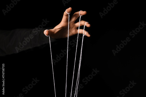 Photos Female hand of puppeteer with strings on dark background