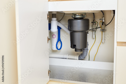 The installation of a functional garbage disposal unit beneath the kitchen sink showcases essential plumbing setup.