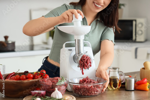 Young woman using meat grin...