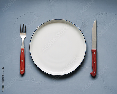 Elegant empty plate with modern utensils on a gray textured backdrop ready for delicious food photography and culinary content