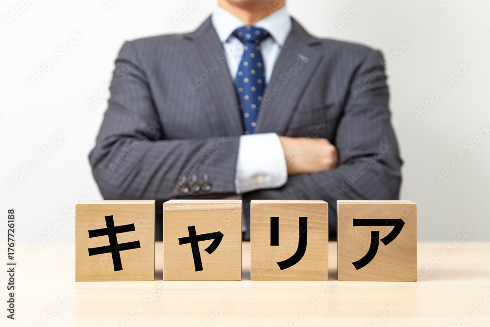Obraz premium 「キャリア」と書かれたブロックと腕組みをするビジネスマン