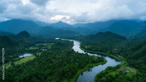 Serene River Winding Through Lush Green Mountainous Rainforest Under Dramatic Cloudy Sky Aerial View