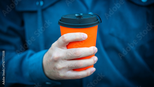 Hand Holding Bright Orange Takeaway Coffee Cup with Black Lid