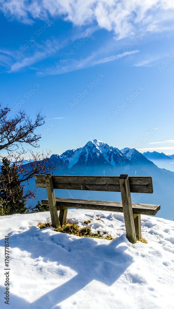 Fototapeta premium Wooden bench on snowy mountaintop under a vibrant blue sky