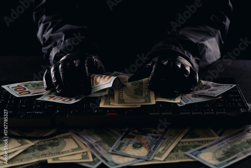 Hacker's hands on a computer keyboard rake in money