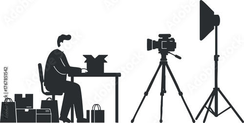 A silhouette of a man working at a desk with a camera setup for photography.