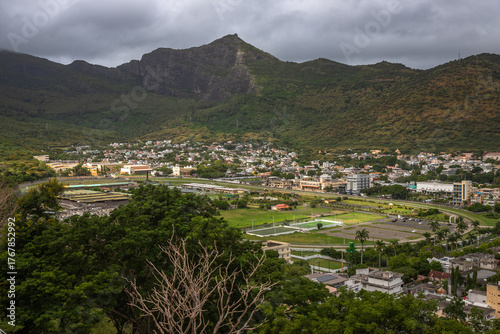 Panoramic view of Port Louis, the capital city of Mauritius, with a dramatic mountain range in the background under moody skies. This urban landscape highlights the contrast 