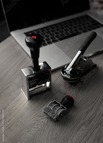 Metal office stamps on desk with laptop in background - vertical photo