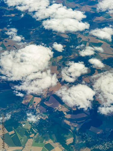 Scenic view of lush farmland and clouds taken from a high altitude during a daytime flight in a clear blue sky