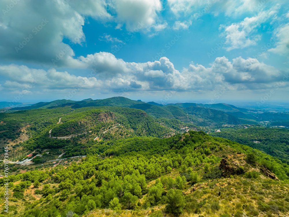 Fototapeta premium Vibrant green hills stretching beneath cloud-covered skies in a serene mountain landscape captured during midday