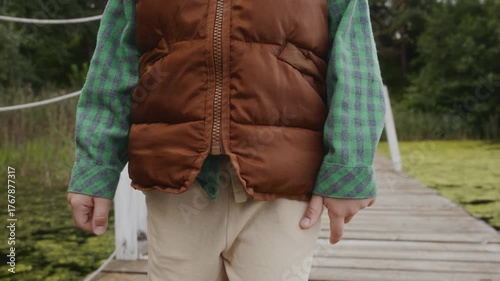 Medium shot of boy walking calmly on wooden pier. Scene reflects outdoor harmony, balance and healthy lifestyle. High quality 4k footage