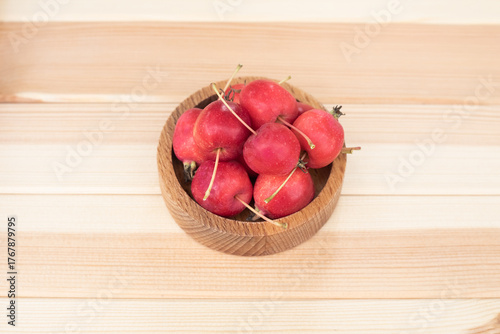 Apples. The fruits of a small-fruited apple tree in a wooden bowl on a light wooden background.