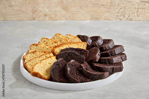 Sliced vanilla and chocolate pound cakes arranged on round white platter.