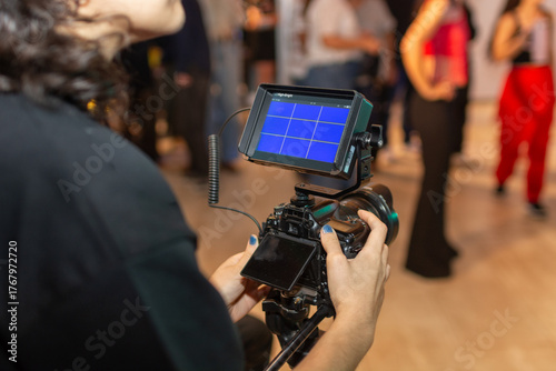 Detalles de manos operario videografo o filmmaker con monitor fondo azul en primer plano	