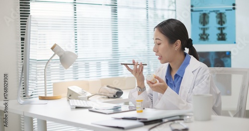 Asian female doctor holding a prescription bottle uses voice AI assistant on smartphone search for drug information. artificial intelligence in healthcare, medication verification, smart health tech.