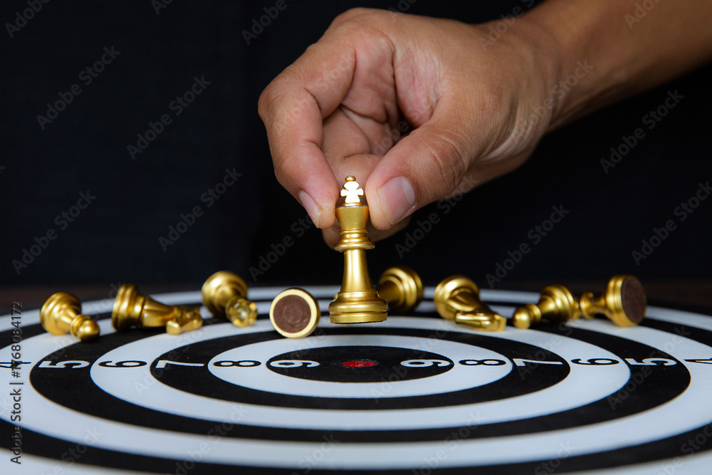 Obraz premium Hand chooses king chess on bullseye center for leadership or wining challenge battle fighting of business team player and risk management or human resource or strategic planning concepts.