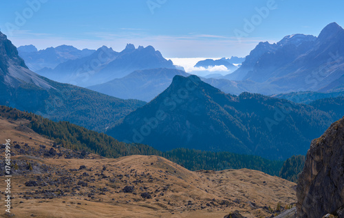 Autumn landscape in Croda da Lago circuit hike in the Ampezzo Dolomites. Large meadow in the foreground, chain of mountain ridges covered by clouds in background. Family vacation in Dolomites, Italy