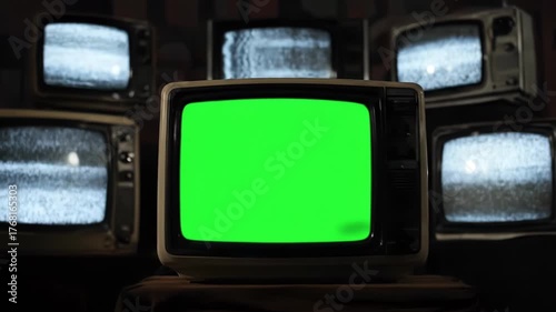A collection of vintage televisions, some displaying static and one with a prominent green screen, creating a retro and nostalgic technological display