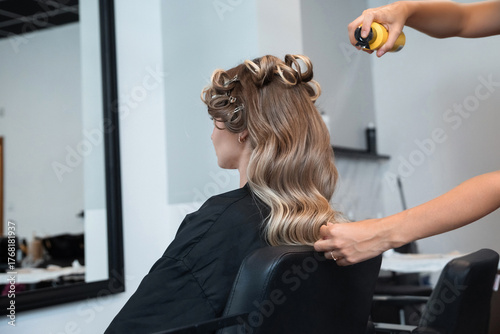 Stylist applies hair spray to create curls during a hair styling session at a salon in the afternoon