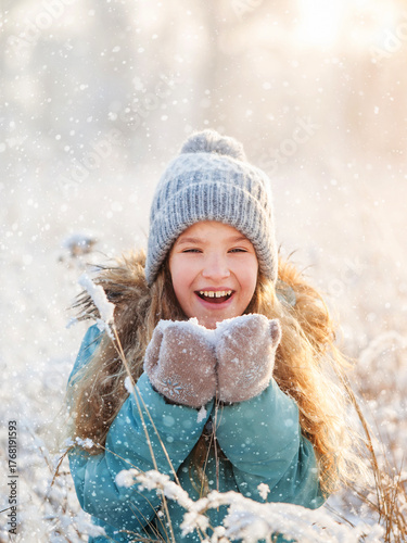 Child walking at winter park. Kid enjoys the snow and the beautiful weather. Happy girl play with snow