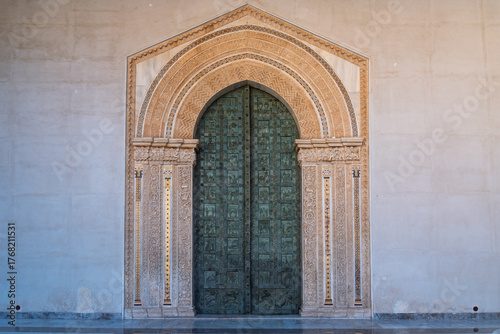 Ornate bronze doors at Monreale Cathedral with biblical scenes and decorative arch