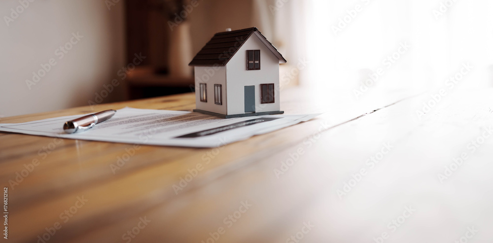 Φωτογραφία Miniature house model placed on real estate documents with a pen on a wooden table, symbolizing property investment and home ownership concept