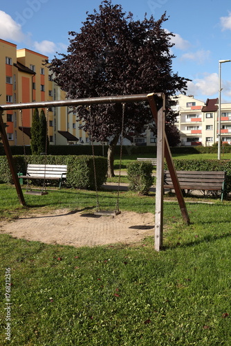 recreation area among urban buildings, European style of building, swings and benches for relaxation in the courtyard of high-rise buildings, beautiful cityscape of a sleeping area, sleeping area