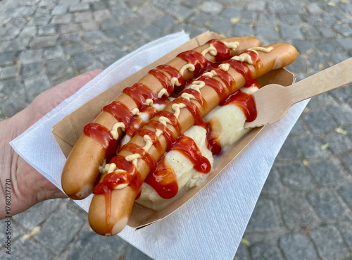 Traditional Swedish hot dogs served with mashed potatoes, ketchup, and mustard in a paper tray