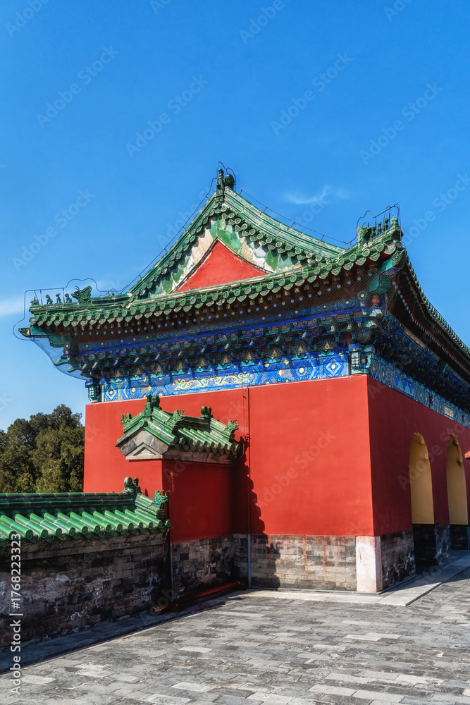 Fototapeta premium Traditional Chinese architecture at the Temple of Heaven, featuring vibrant red walls and distinct green-tiled roofs