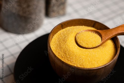 Obraz na plátně Delicious corn grits in a wooden bowl with a spoon on a kitchen countertop