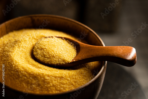 Obraz na plátně Corn grits in a wooden bowl with a spoon ready for cooking or serving