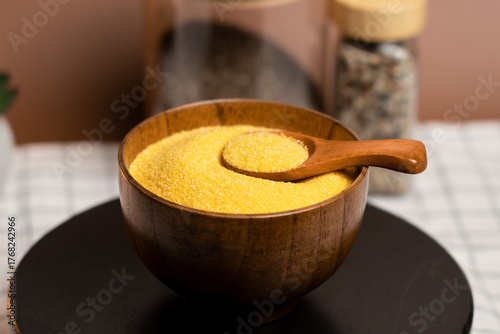 Corn grits in a wooden bowl with a spoon on display in a cozy kitchen setting