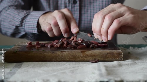 Man cutting marinated olives on a wooden board - Mediterranean breakfast concept