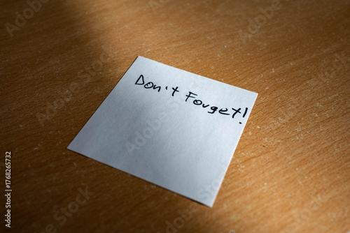Canvas Print White paper note with don't forget text on a table in harsh sunlight