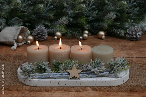  Arrangement für den dritten Advent : Dekoration mit vier beigen Adventskerzen, Tannenzweigen und Weihnachtskugeln.