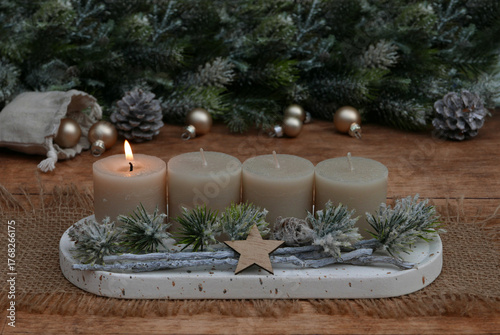  Arrangement für den ersten Advent : Dekoration mit vier beigen Adventskerzen, Tannenzweigen und Weihnachtskugeln.