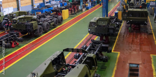 Military vehicle assembly in a factory showcasing multiple vehicles and equipment during daytime operations