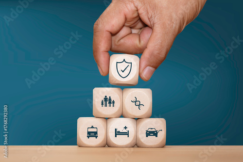 Fotografie Hand stacking wooden blocks with blue insurance icons representing health, family, home, travel, and life protection