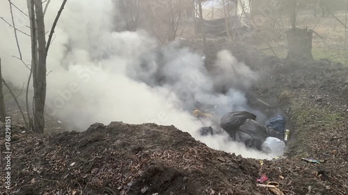 the garbage was dumped into a pit and set on fire. Wrong, harmful to nature and people - toxic smoke, live branches are burning.