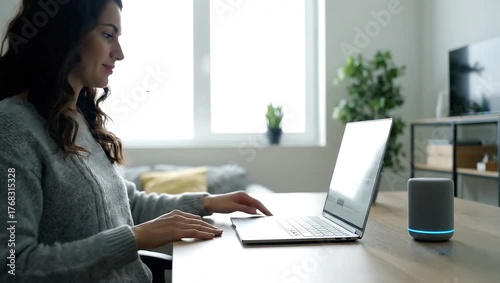 Woman using laptop and smart speaker at home, remote work with modern voice assistant technology