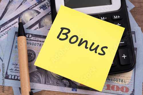 Adhesive note with text bonus on top of US financial bill  business concept